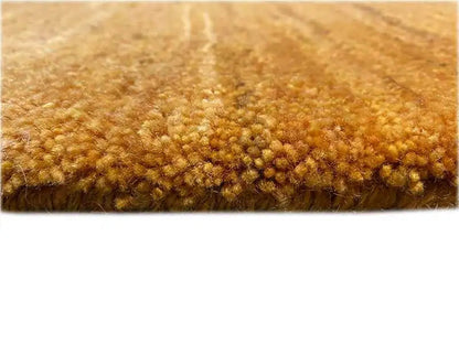 Gabbeh rug, detail of the golden-brown pile with a dense, irregular texture.