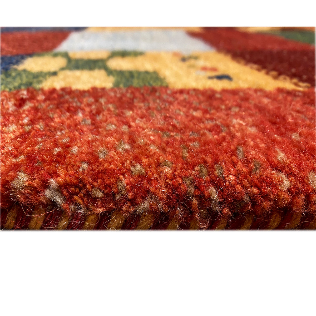Close-up of the Gabbeh rug: dense pile with a reddish surface and colorful flecks