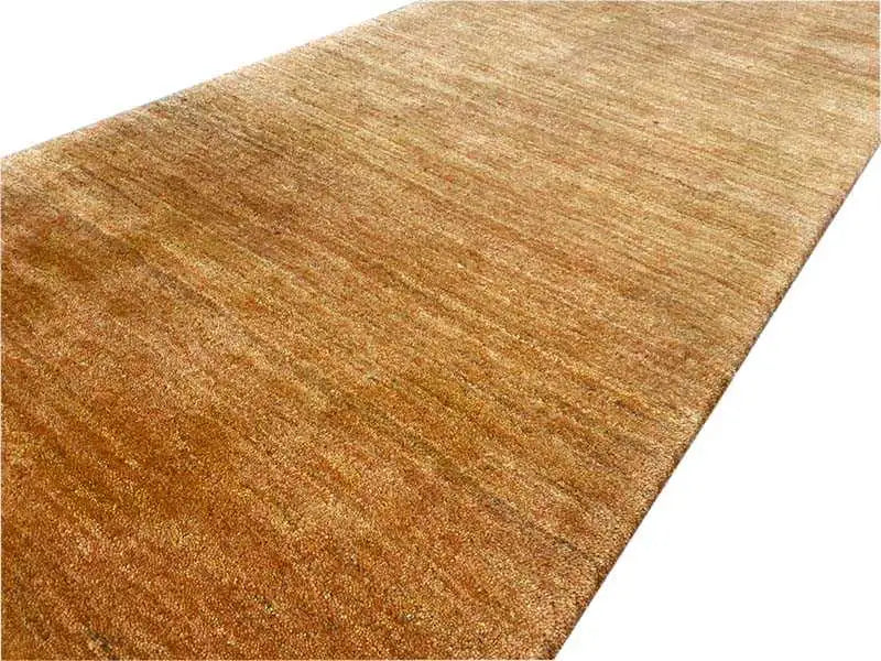 Close-up: honey-brown Gabbeh runner rug with a fine, textured surface.
