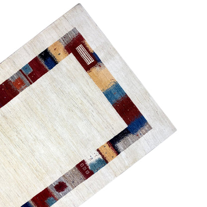 Hand-knotted Gabbeh rug detail: cream-colored pile with a colorful decorative border stripe