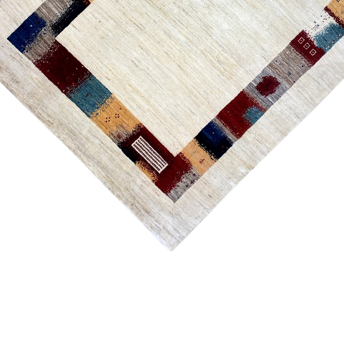 Hand-knotted Gabbeh rug close-up with a cream-colored center and blue, red, and yellow accents