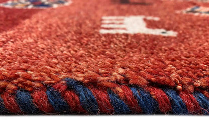 Gabbeh rug edge detail: red pile height with a blue decorative stripe and fringe