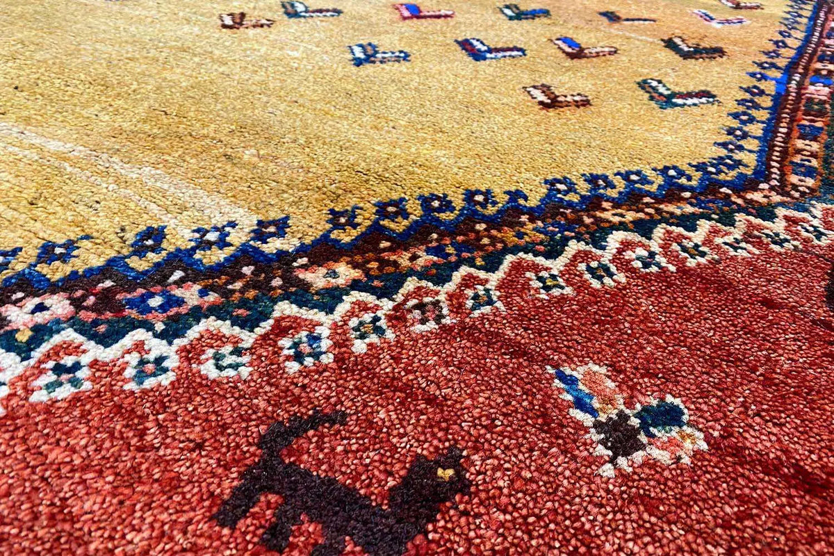 Close-up of the pattern: red pile with a blue border frieze and multicolored motifs
