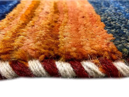 Close-up of a Gabbeh rug: dense pile and fringed edge in red and orange