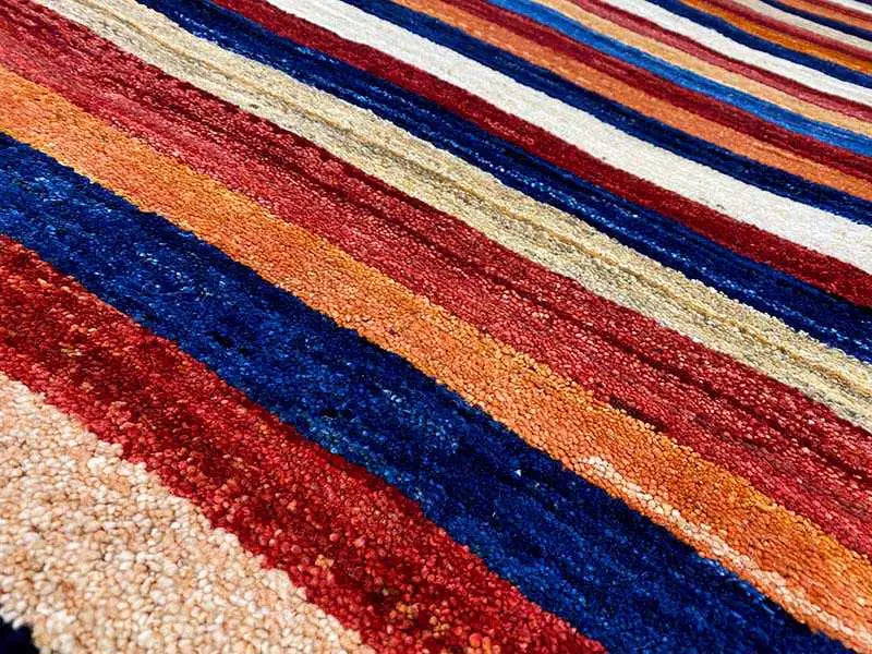 Gabbeh rug detail: striped wool texture in blue, red, and beige