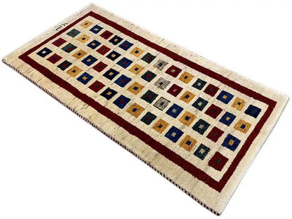Gabbeh rug, laid horizontally: geometric checked pattern with a red border in cream and blue