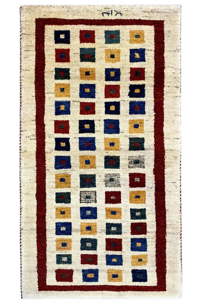 Gabbeh rug, photographed upright: rectangular diamond pattern with a red border and blue
