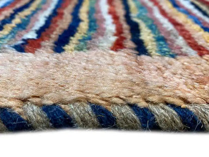 Close-up of a carpet edge with fringes and a multicolored striped selvedge