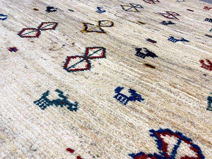 Close-up of a Gabbeh rug: beige background with colorful diamond and animal motifs