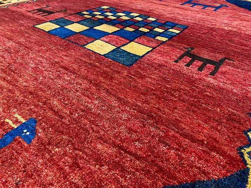 Gabbeh rug detail: red fabric with a blue-and-yellow checked ornament