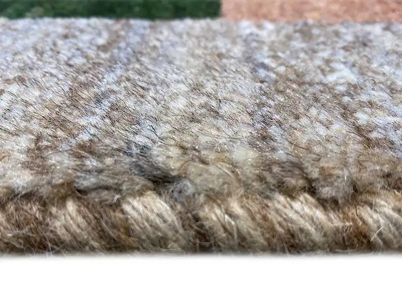 Gabbeh rug close-up: dense, textured pile fibers in a beige-brown tone
