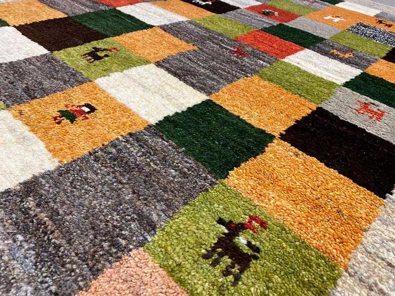 Gabbeh rug detail: colored square panels with animal motifs, visible pile texture