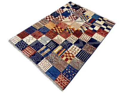 Rectangular Gabbeh rug with blue, red, and cream patchwork, with fringes along the edges