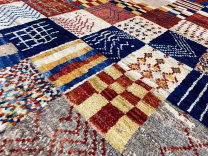 Gabbeh rug close-up: patchwork squares with blue, red, and cream ornaments
