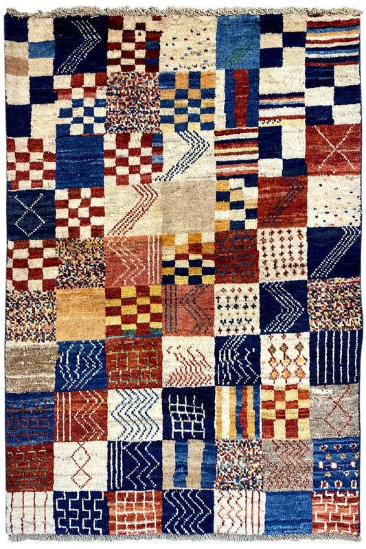 Gabbeh rug with a patchwork look featuring many tile patterns in blue, red, and cream