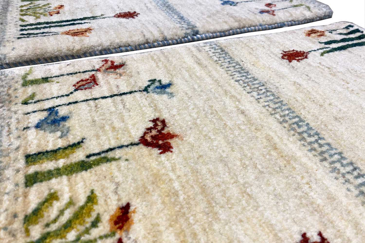 Close-up: cream-colored rug with colorful floral motifs and a blue decorative border