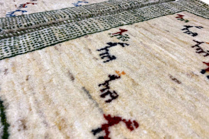 Close-up of pile: beige background with multicolored animal motifs and a gray-green woven pattern