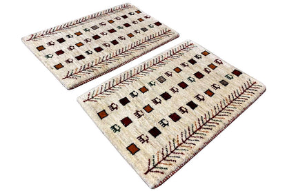 Two cream-colored Gabbeh rugs with a square pattern and red decorative borders