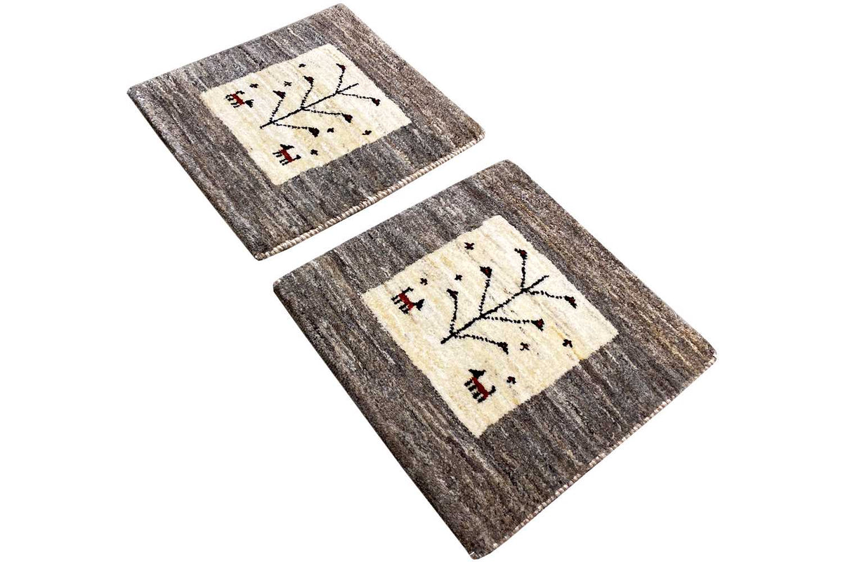 Gabbeh rug (2-piece view) with a beige field and black tree motif on a gray background