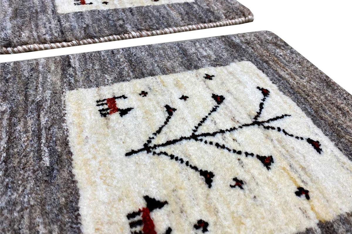 Detail view: Gabbeh rug with a beige tree motif and hand-stitched edge on a gray pile