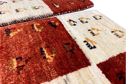 Gabbeh rug detail, reddish-brown and cream fields, multicolored motifs along the edge