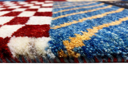 Close-up of the Gabbeh rug: blue-and-white and red patterns, visible pile texture