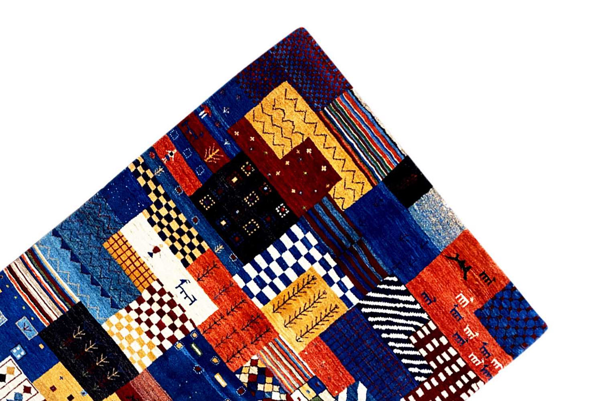 Gabbeh rug viewed at an angle with patchwork blocks in blue, red, and yellow