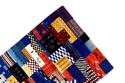 Gabbeh rug viewed at an angle with patchwork blocks in blue, red, and yellow
