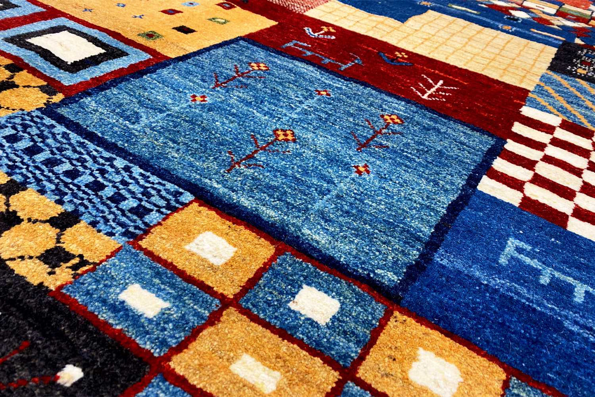 Close-up of the Gabbeh rug: blue field with red embroidered lines and yellow accents