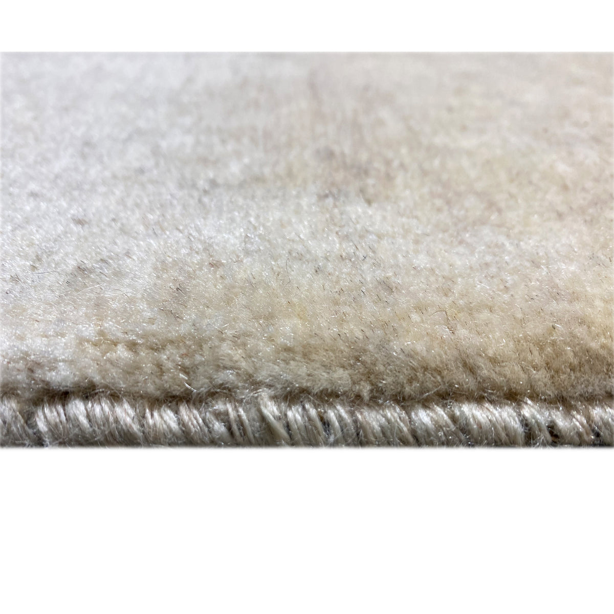 Close-up of the pile edge: beige Gabbeh rug with short pile.