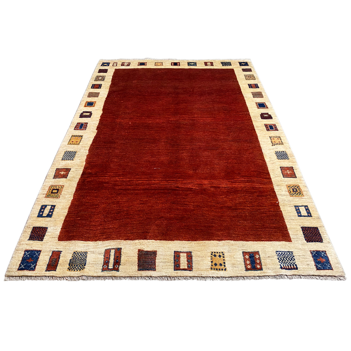 Gabbeh rug in three-quarter view: red central area, beige border with repeated motif bands