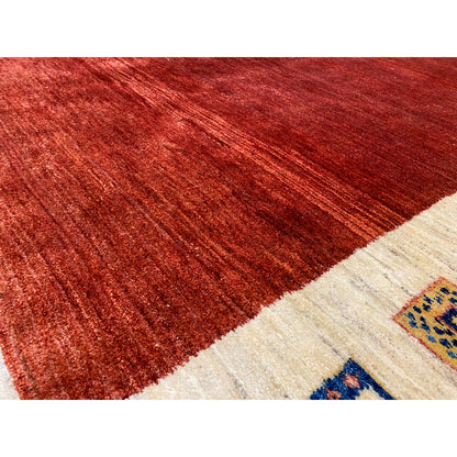Gabbeh rug close-up: reddish-brown pile surface with a beige border area