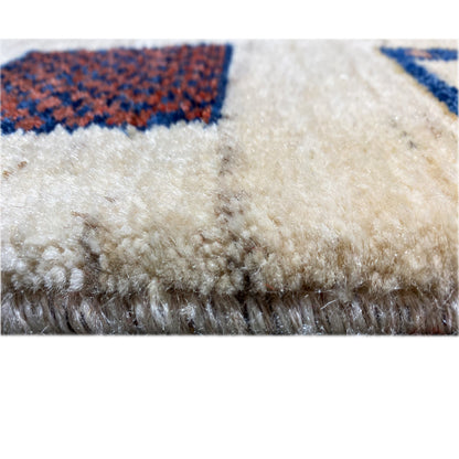 Gabbeh rug close-up of the pile: dense, beige wool fabric with a red accent