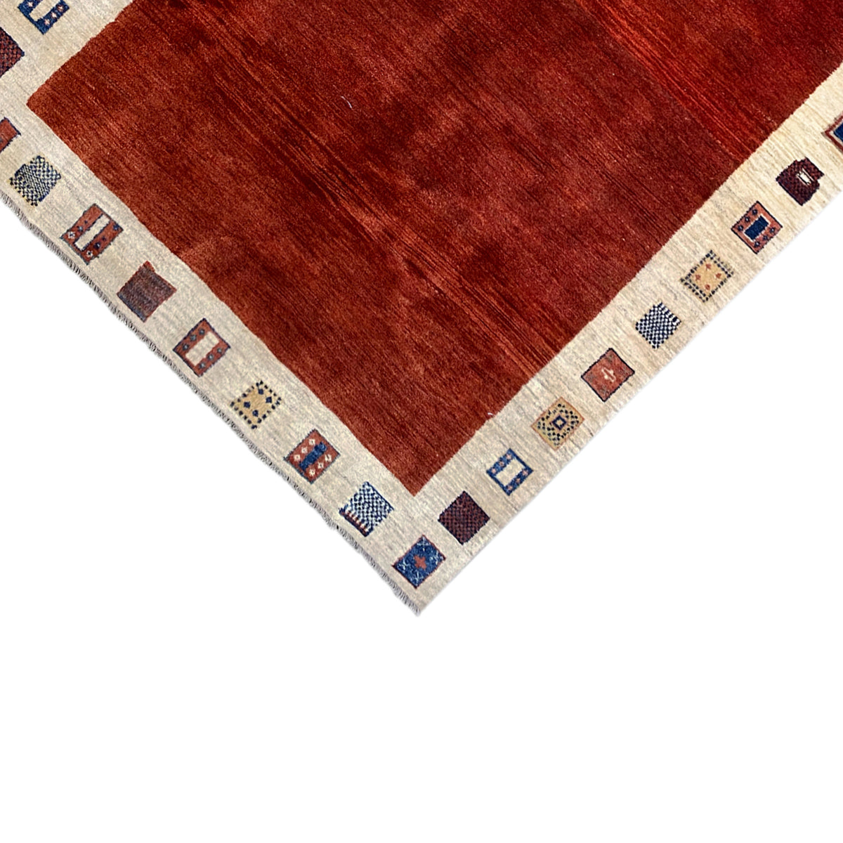 Gabbeh rug edge view: red pile with a beige border and small patterned squares