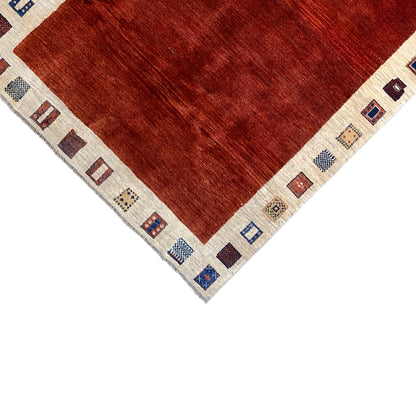 Gabbeh rug edge view: red pile with a beige border and small patterned squares
