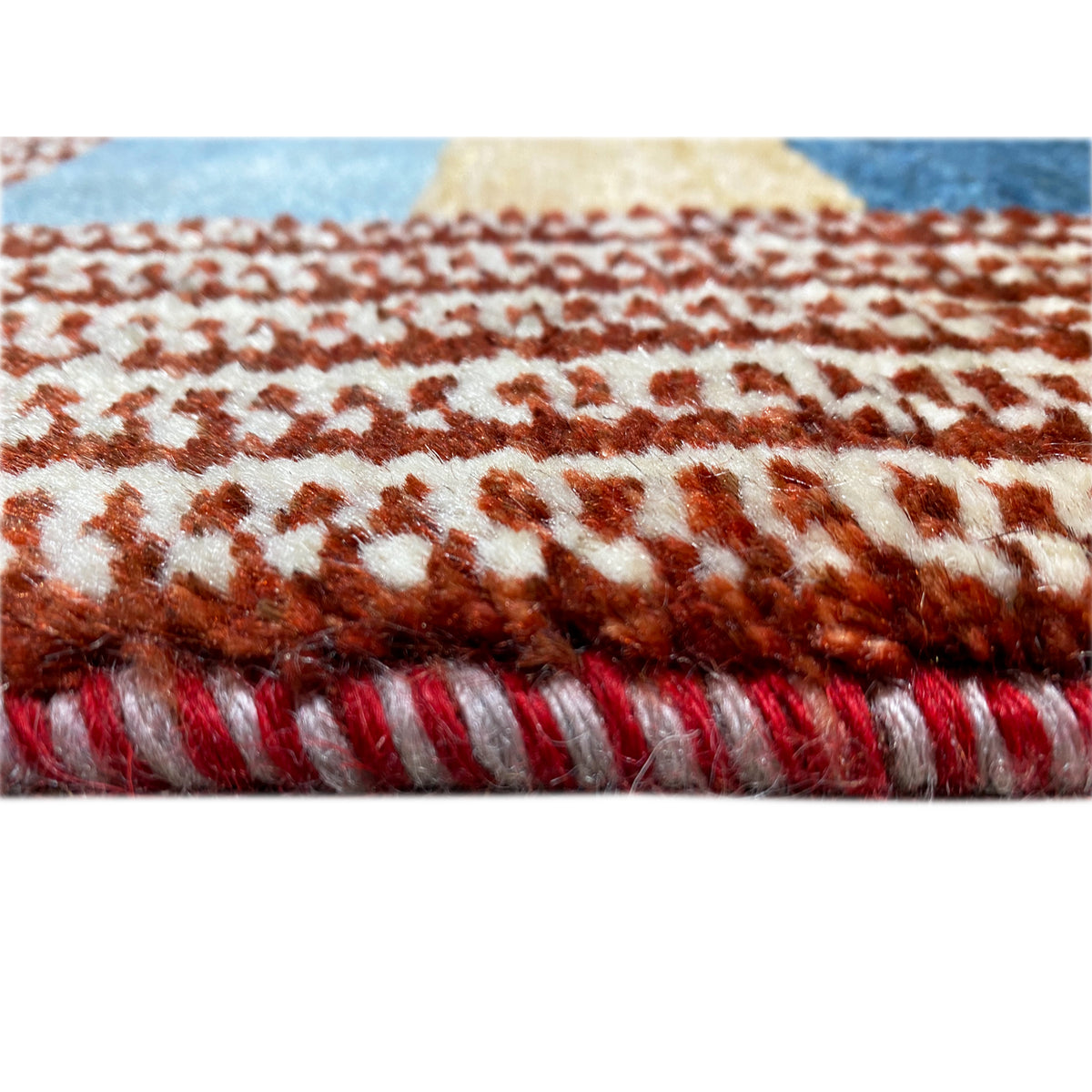 Gabbeh rug edge detail with fringes in reddish brown and a light background