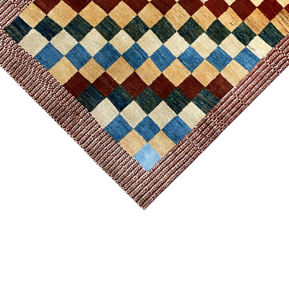 Gabbeh rug corner with a multicolored checkered pattern and reddish-brown decorative stitched border