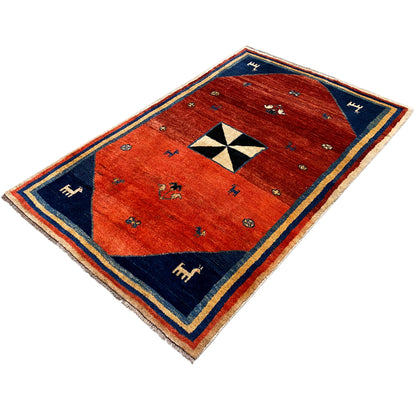 Gabbeh rug viewed diagonally: red center, framed in blue, animal figures and border
