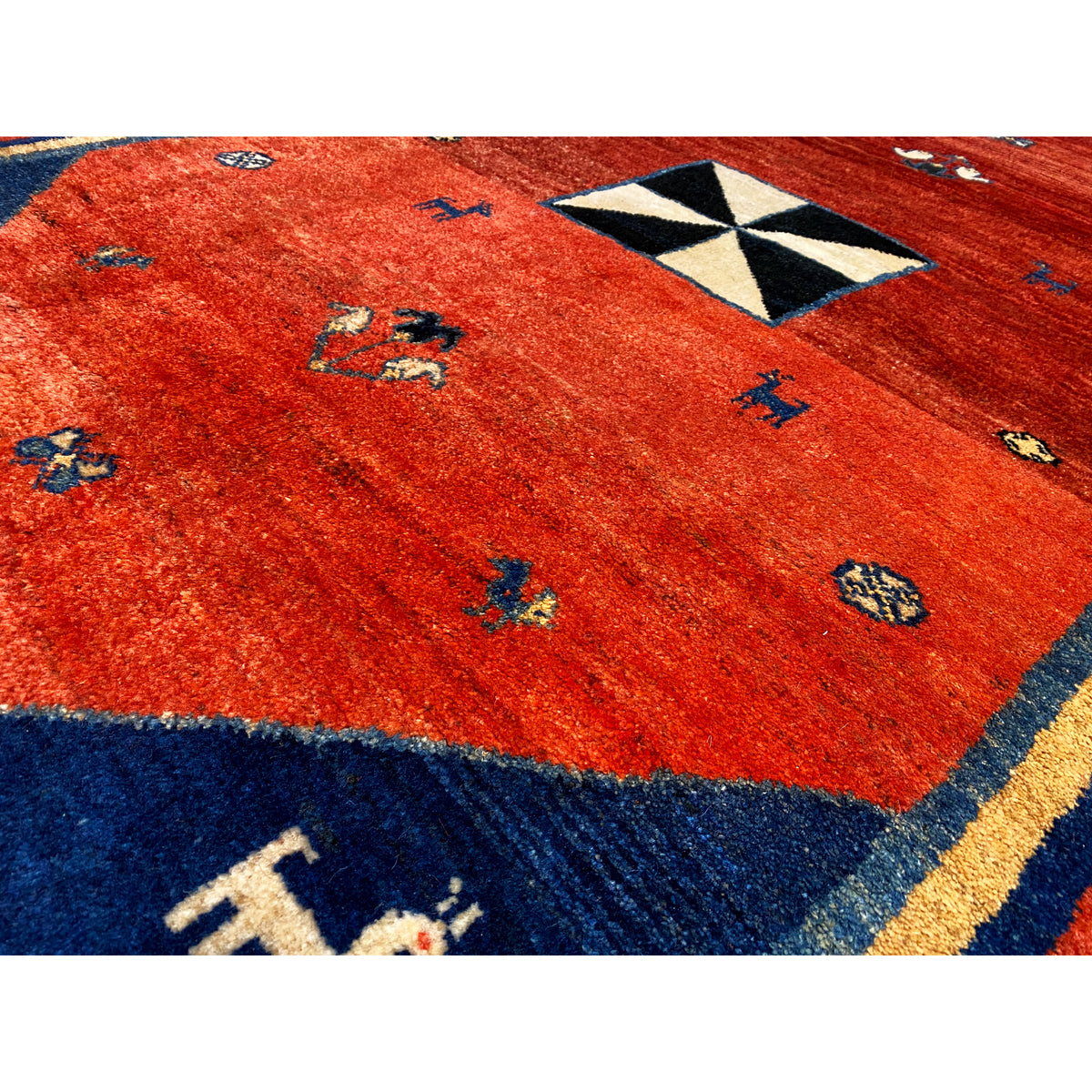 Close-up of carpet: reddish-brown fabric with small colorful animal motifs