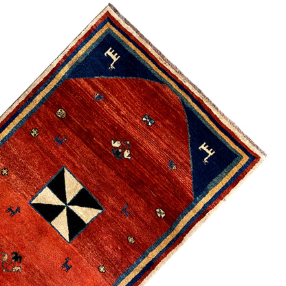Corner of the rug: red field, blue border band, black-and-white octagonal pattern