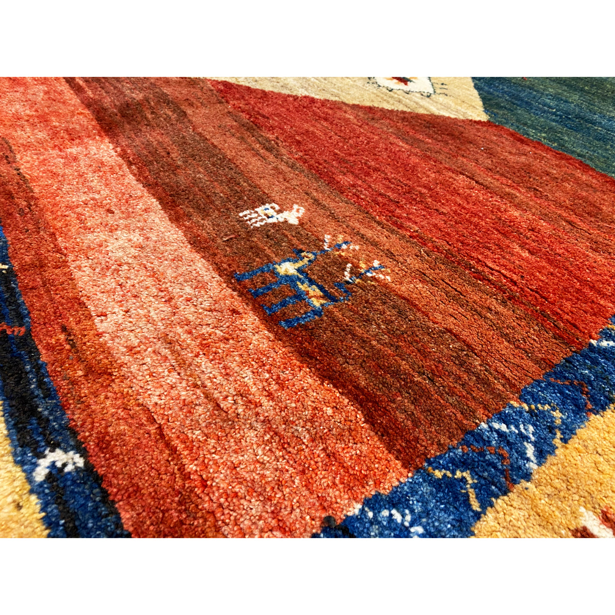 Close-up of a Gabbeh rug: reddish-brown surface with a fine pile and blue border ornaments