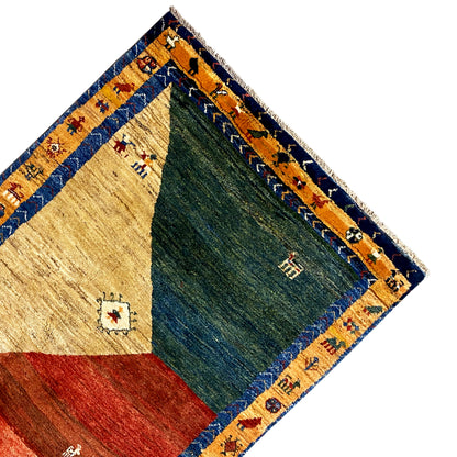 Gabbeh rug corner with a blue border, beige and green areas, small ornaments