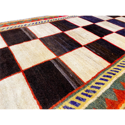 Gabbeh rug close-up: diamond pattern in cream, black, and dark blue, multicolored decorative borders