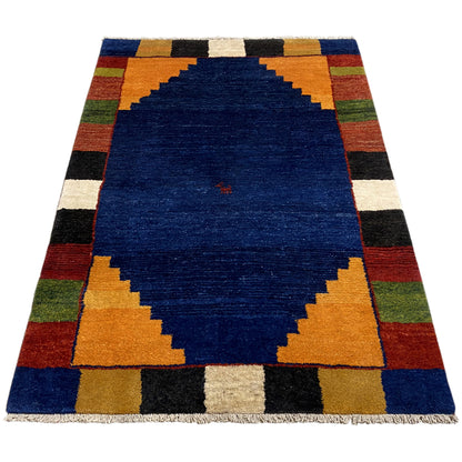 Rectangular rug with a blue center and a checked border in orange, green, and black.