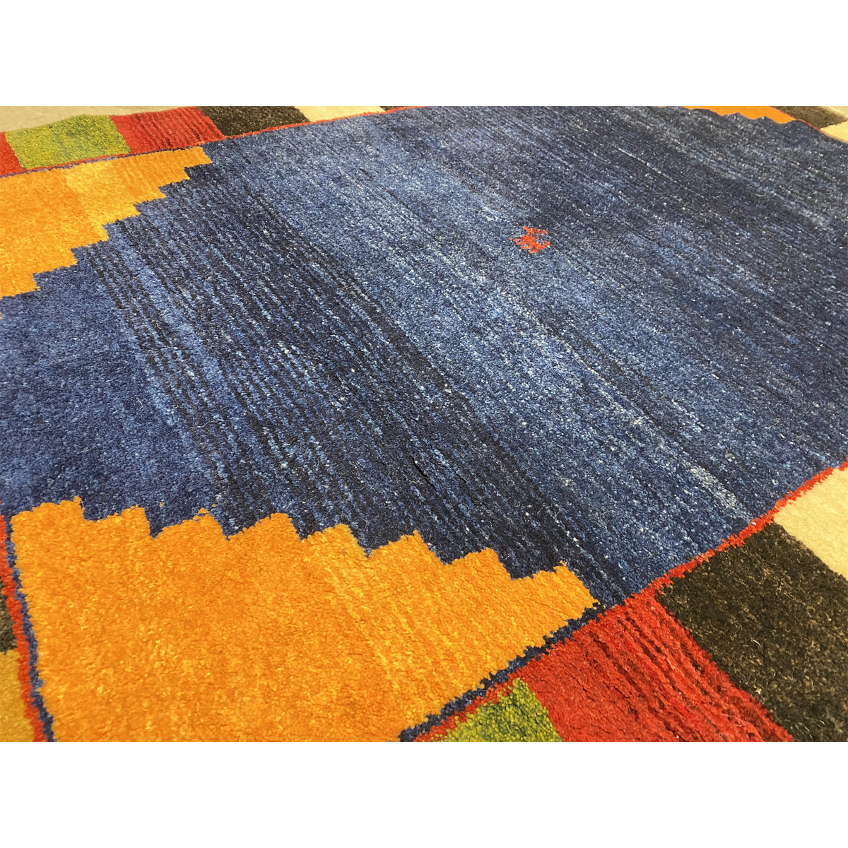 Detail of the carpet pile: mottled blue with orange zigzags and colored blocks.