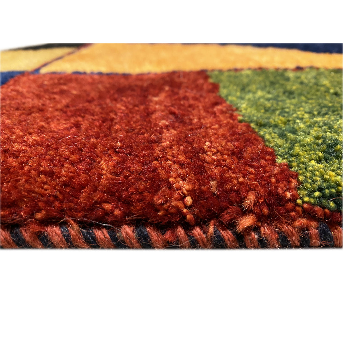Carpet pile detail with a reddish-brown area and green accent next to an orange-yellow area.