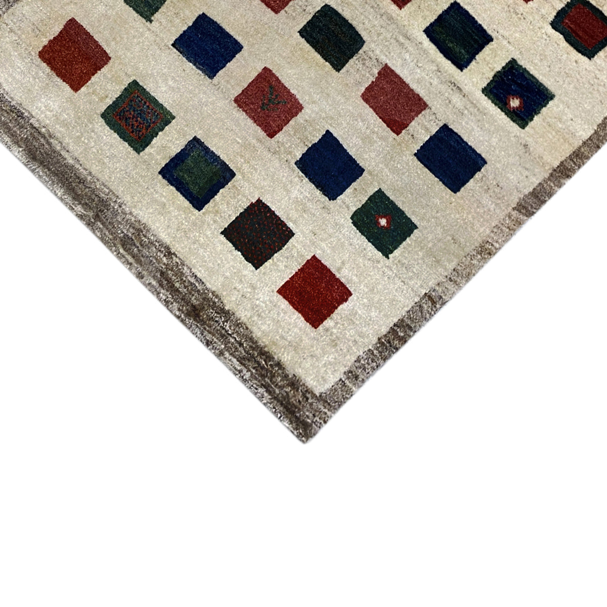 Gabbeh rug corner view: square pattern in blue, red and green on a beige background