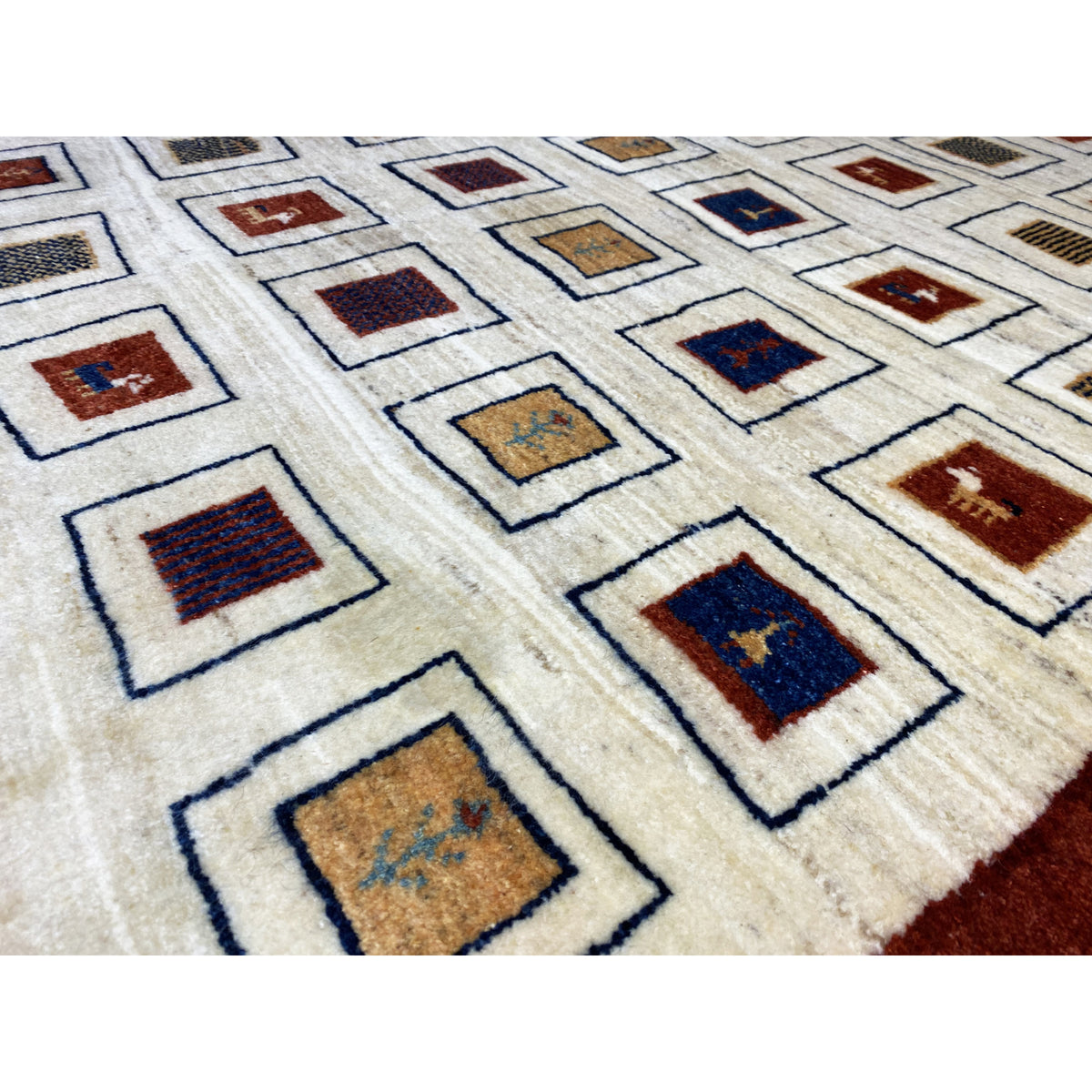 Close-up of a Gabbeh rug: cream-colored background with blue-red squares in the pattern