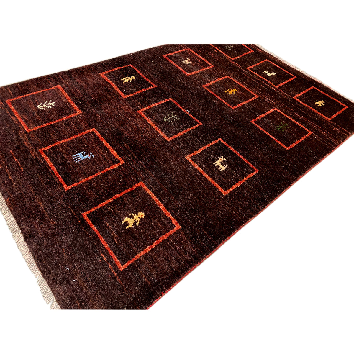 Gabbeh rug, detail: brown pile with red squares and woven-in animal motifs