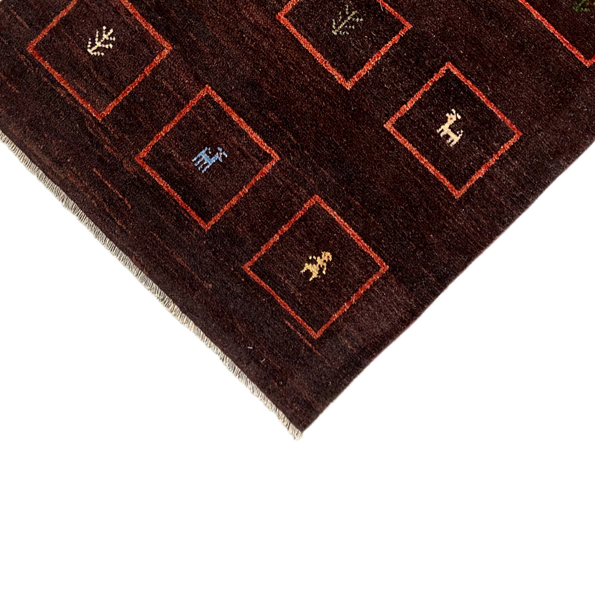 Close-up of rug edge: brown pile, red square borders, and bound fringes
